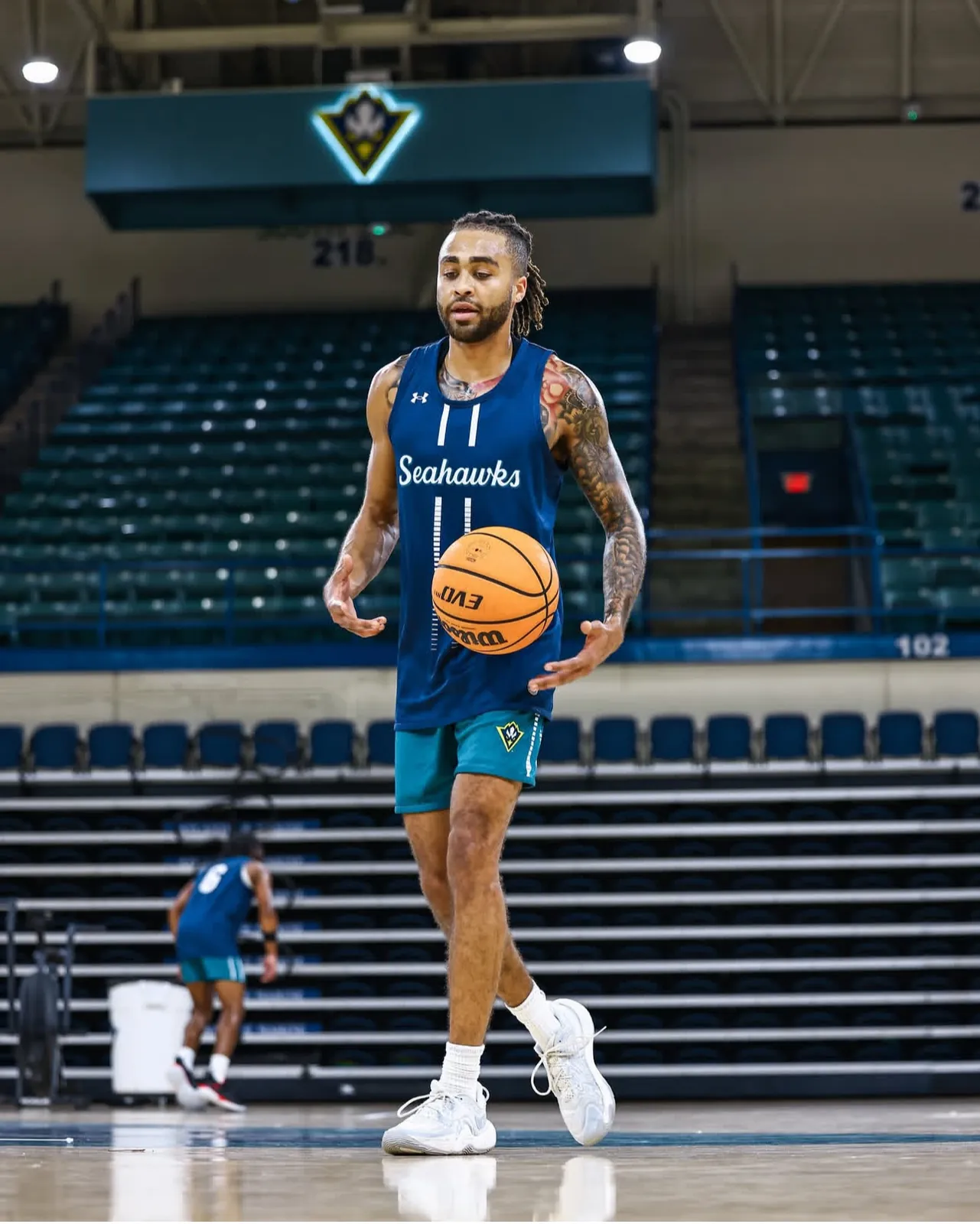 CJ Luster II standing on the UNCW court with a basketball